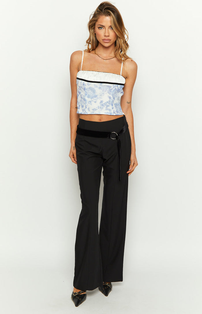 Front view of a blue and white toile print crop top with a straight neckline, white satin band, and thin spaghetti straps