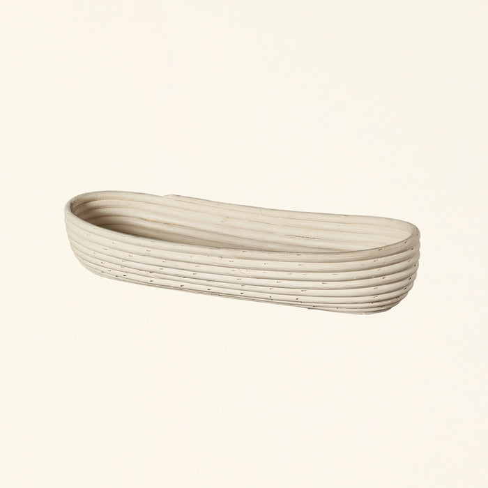 Natural rattan basket with a long, thin shape.