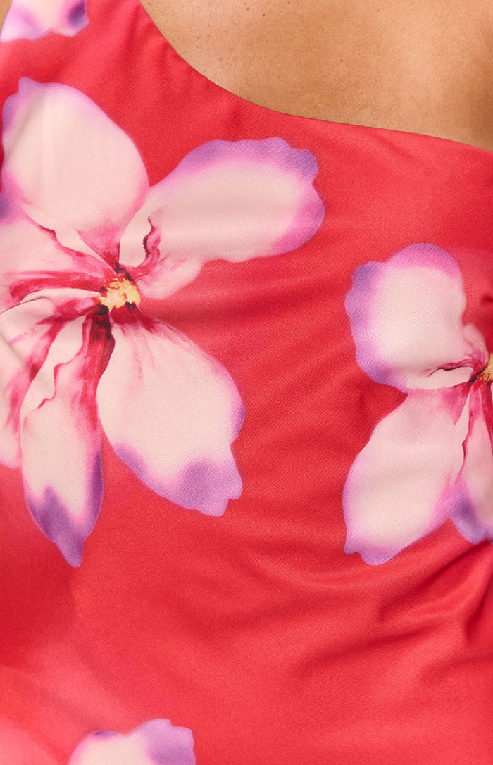 Close-up of the red fabric with large pink and purple floral print and a hint of the asymmetric neckline