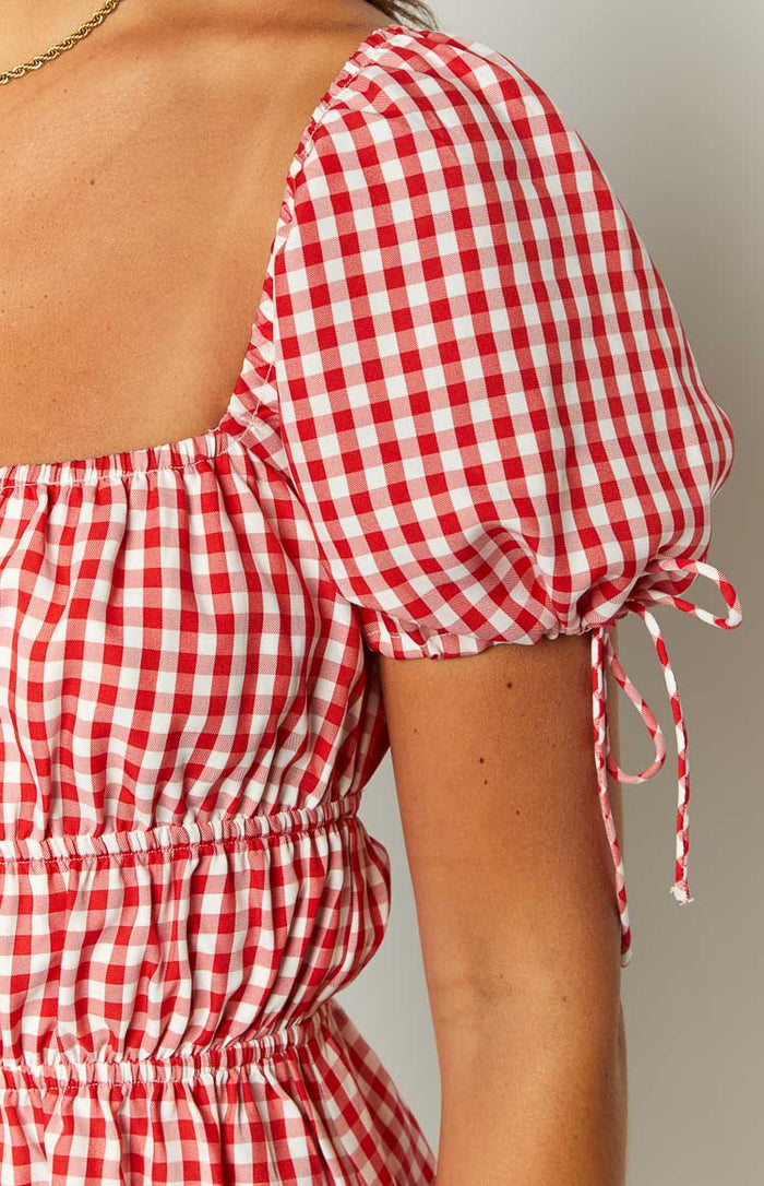 Close-up of the red gingham mini dress showing the square neckline, puffed sleeves with drawstring ties, and shirred waist