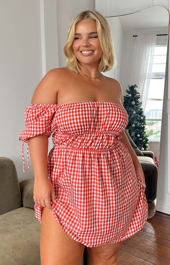Front view of a red gingham off-shoulder mini dress with shirred bust, elasticated waist, and tie sleeves