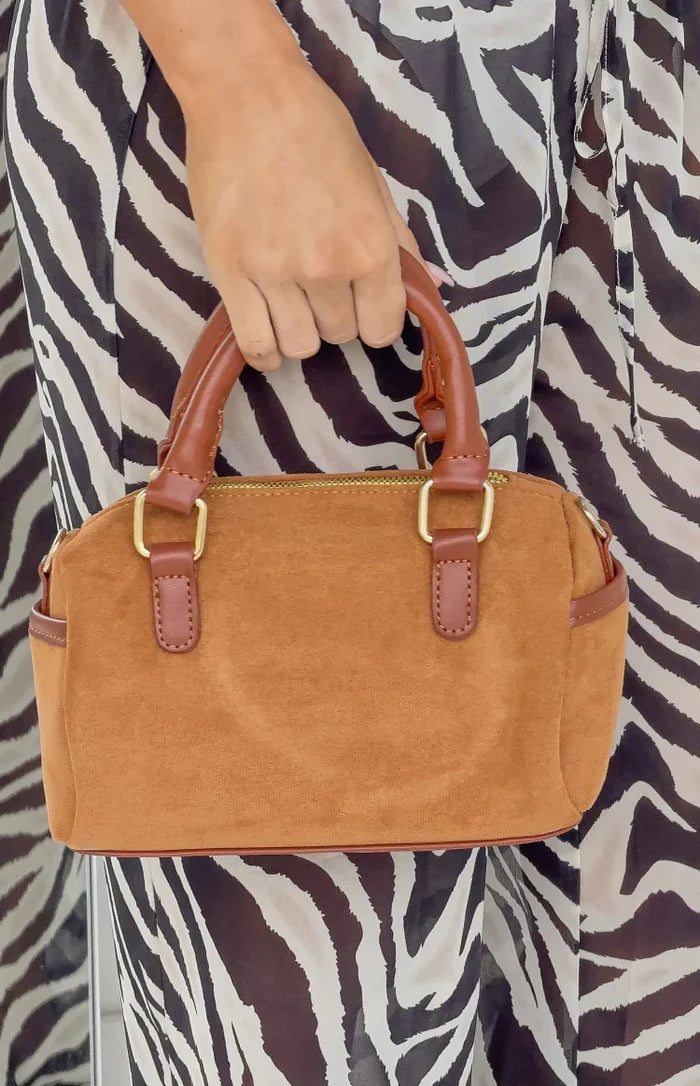 Close-up of the brown suede shoulder bag, showing the brown leather top handles and gold hardware