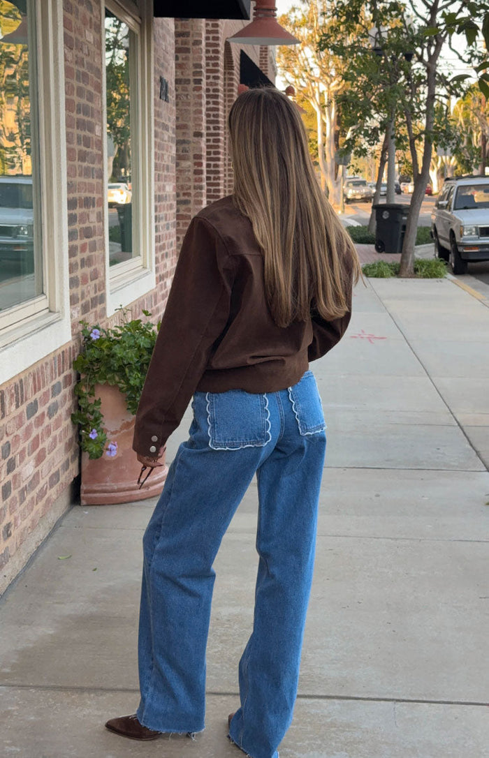 Rear view of mid-wash jeans with white scalloped back pockets and wide legs