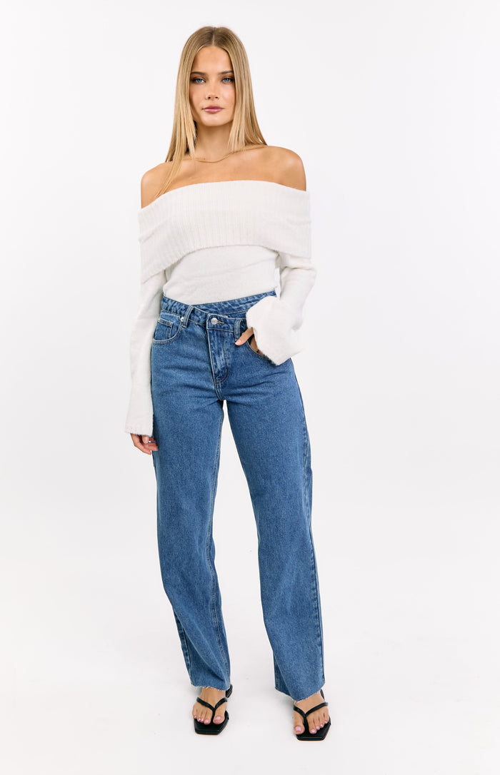 Front view of mid wash jeans with an uneven crossover waist and straight leg fit