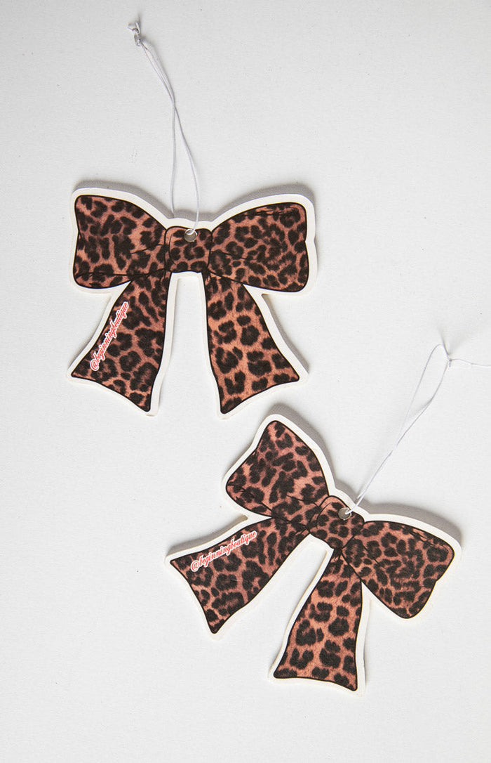 Two leopard print bow air fresheners with white hanging strings and brand text