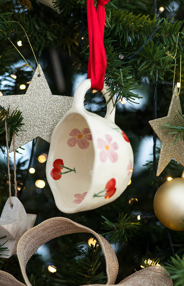 Side and interior view of a cream ceramic mug with red cherry and pink floral patterns