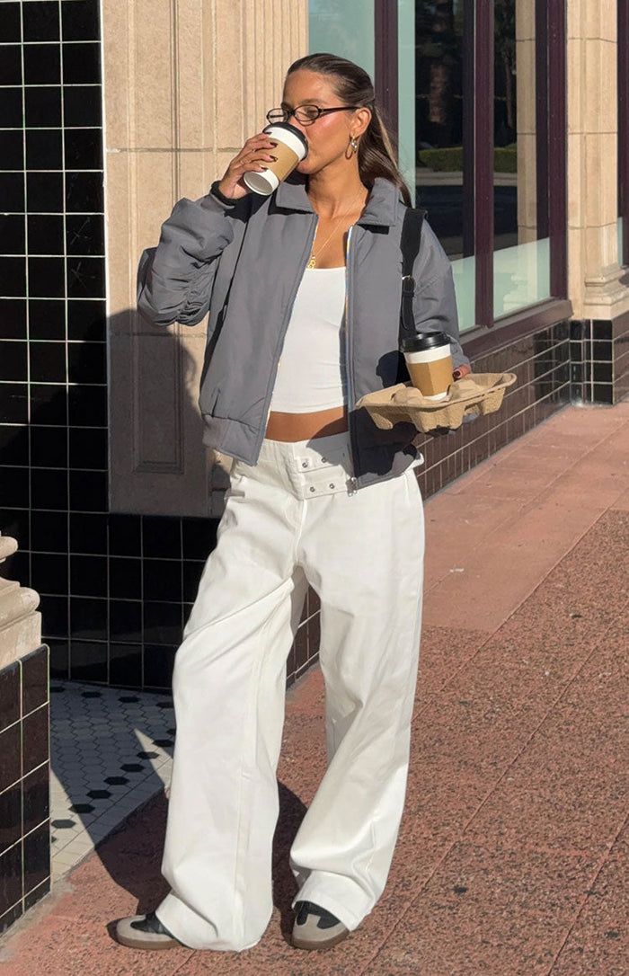 Front view of off-white wide-leg pants with a relaxed fit and prominent double buckle details at the front waist