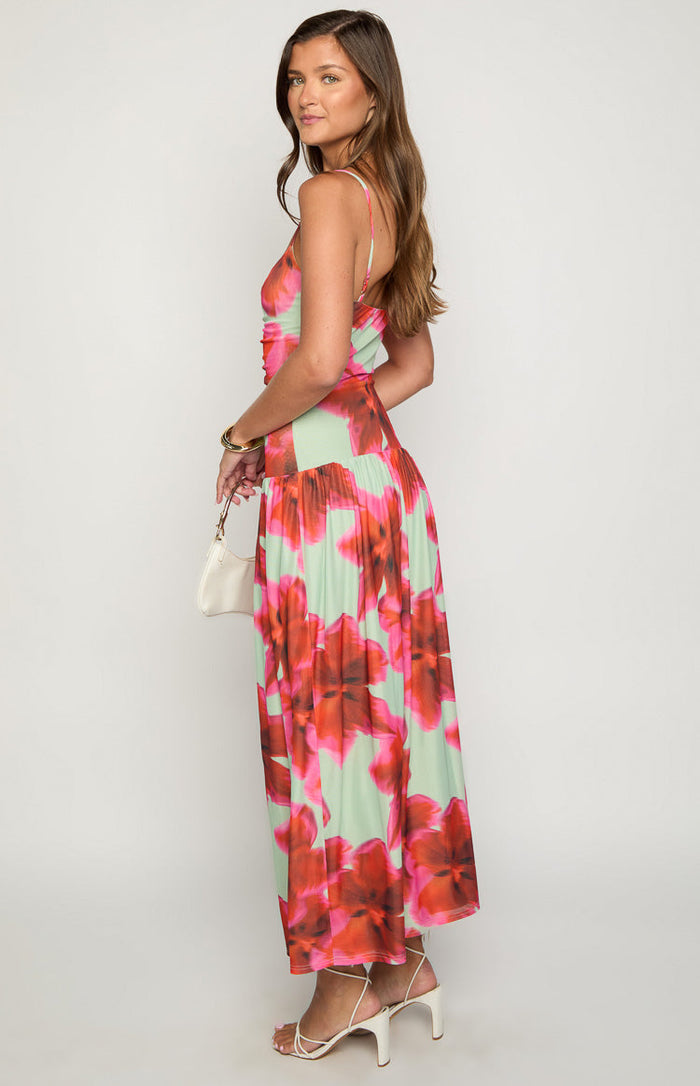 Side view of a green maxi dress with large pink and red floral print, showing the ruched bodice and flowy skirt