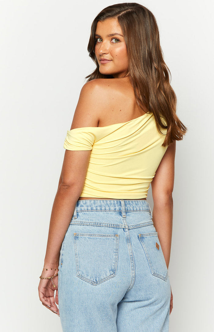 Rear view of the yellow draped off-shoulder crop top with one short sleeve and a cropped hem