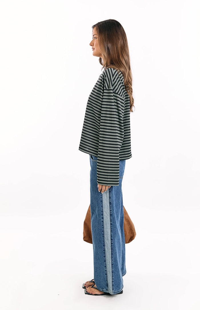 Side view of a forest green and black striped long sleeve top with a relaxed fit and long sleeves