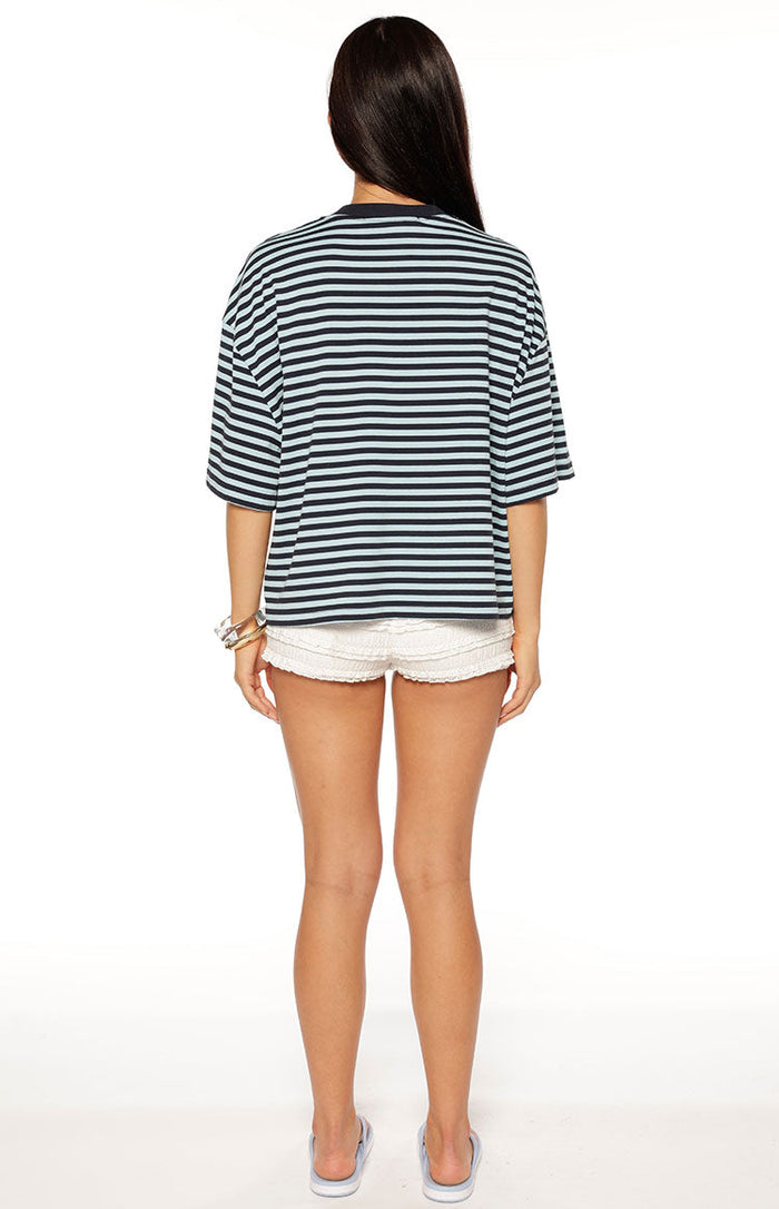 Rear view of the navy and light blue striped short sleeve top with a relaxed, oversized fit and dropped shoulders