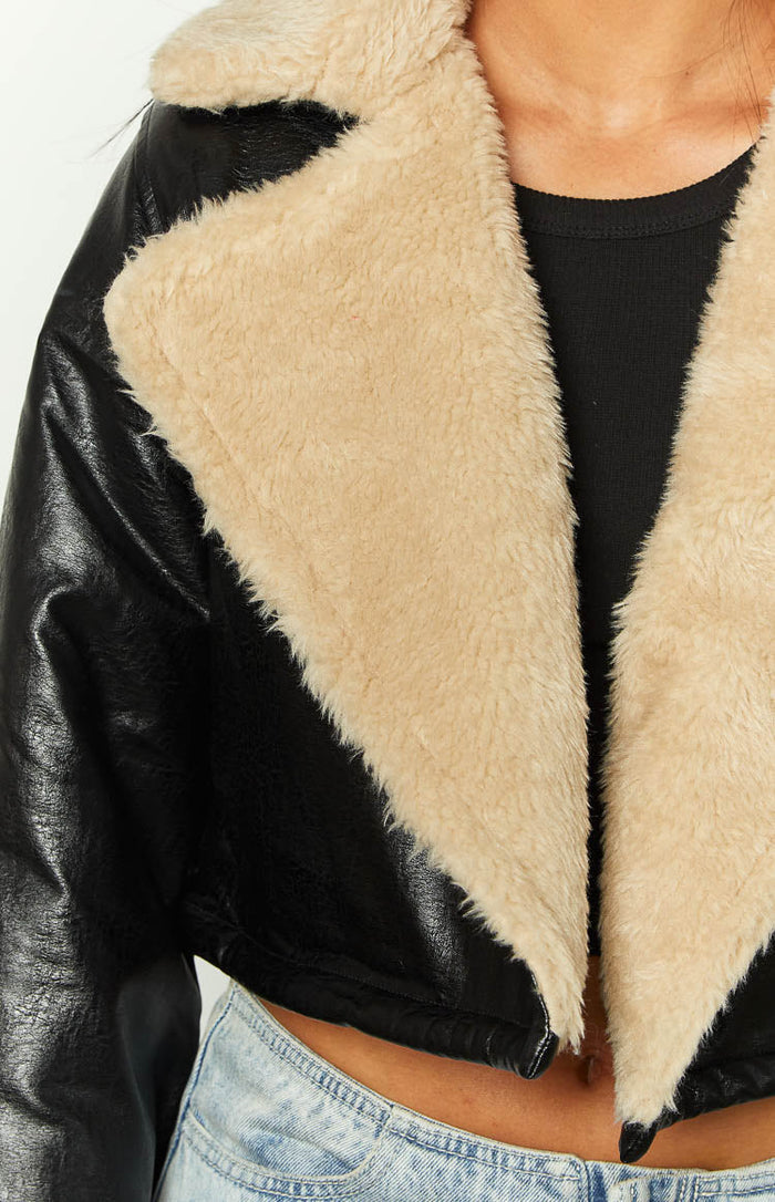 Close-up of the black faux leather jacket with a wide cream faux fur collar
