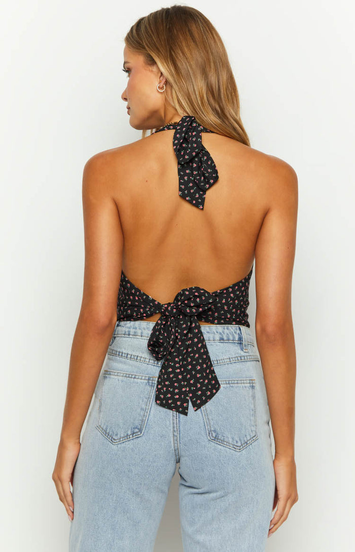 Rear view of a black floral crop top with a halter neck tie and a tie-back closure at the waist
