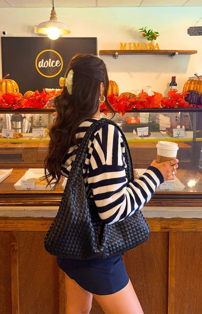 Side view of a navy and white striped knit sweater showing the pattern on the long sleeves