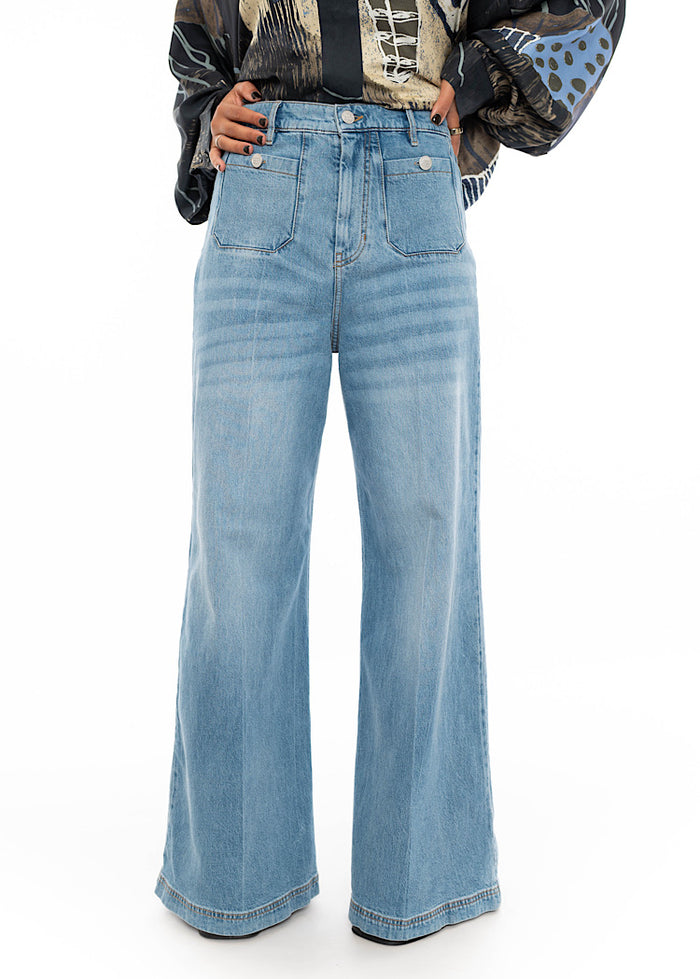 A model wearing straight leg jeans with a patterned silk shirt. Showing front pockets and metal buttons for accents.