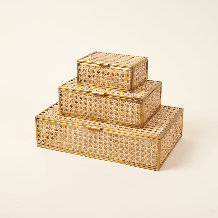A set of three natural cane and glass decor boxes in different sizes.