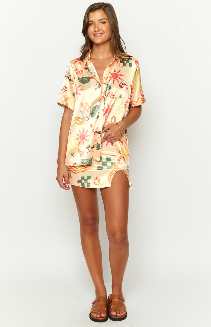 Yellow satin mini skirt with a colourful sun, lime, and checkered print and a high side slit