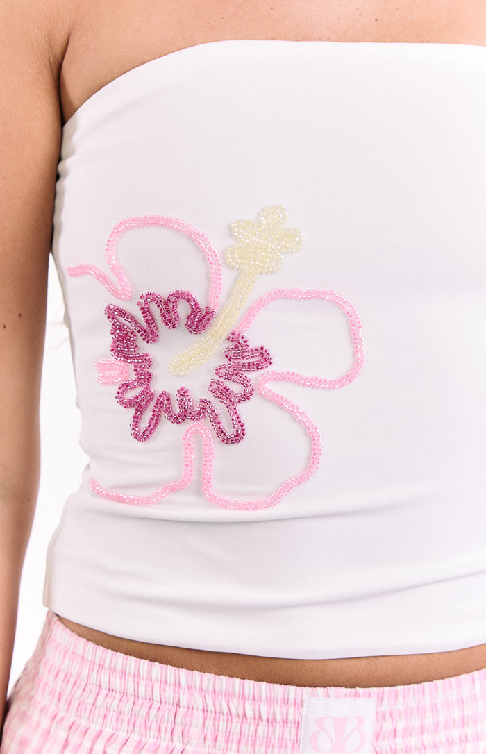 Close-up of the white strapless top featuring a pink, fuchsia, and cream beaded hibiscus flower design