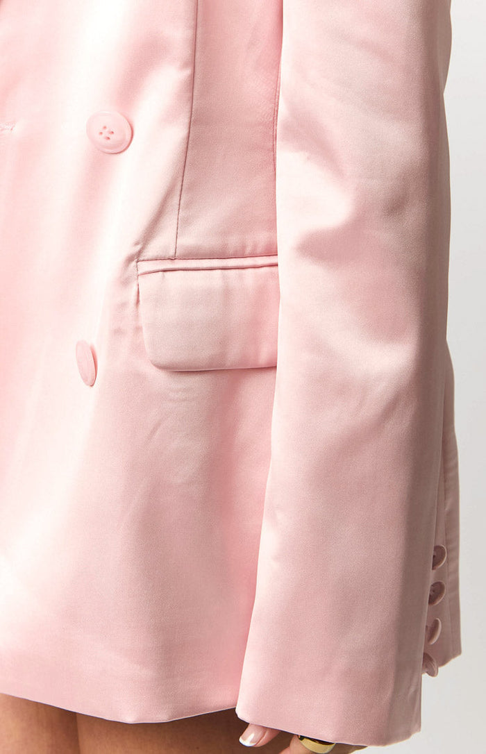 Close-up of the rose pink satin blazer with double-breasted buttons, a flap pocket, and three cuff buttons
