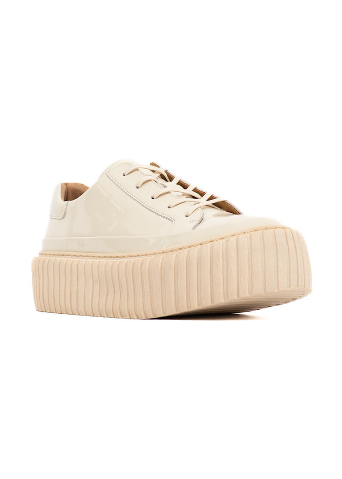 A picture of a light Creme glossy patent leather Shoe. Showing the platform sole adding height and definition and a classic lace up.