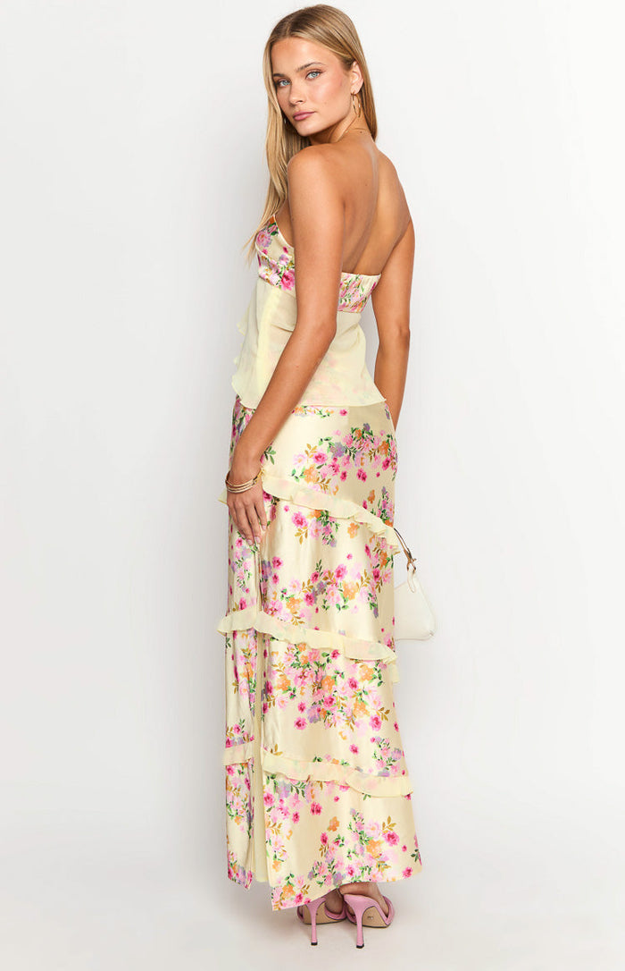Side view of a yellow floral print satin maxi skirt with tiered ruffles along the side
