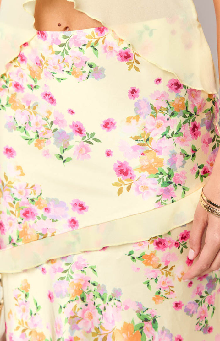 Close-up of the yellow maxi skirt fabric with a pink and orange floral print and a layered ruffle detail