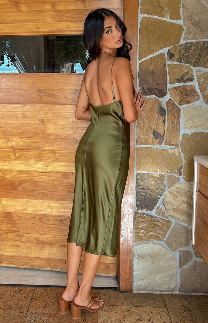 Rear view of a khaki satin midi dress with a low back, thin adjustable straps, and a subtle side slit