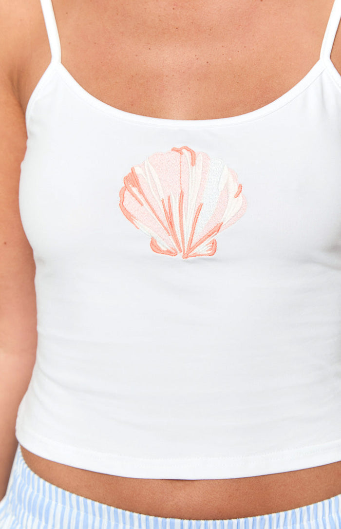 Close-up of the embroidered coral and white shell motif on the front of a white cami singlet