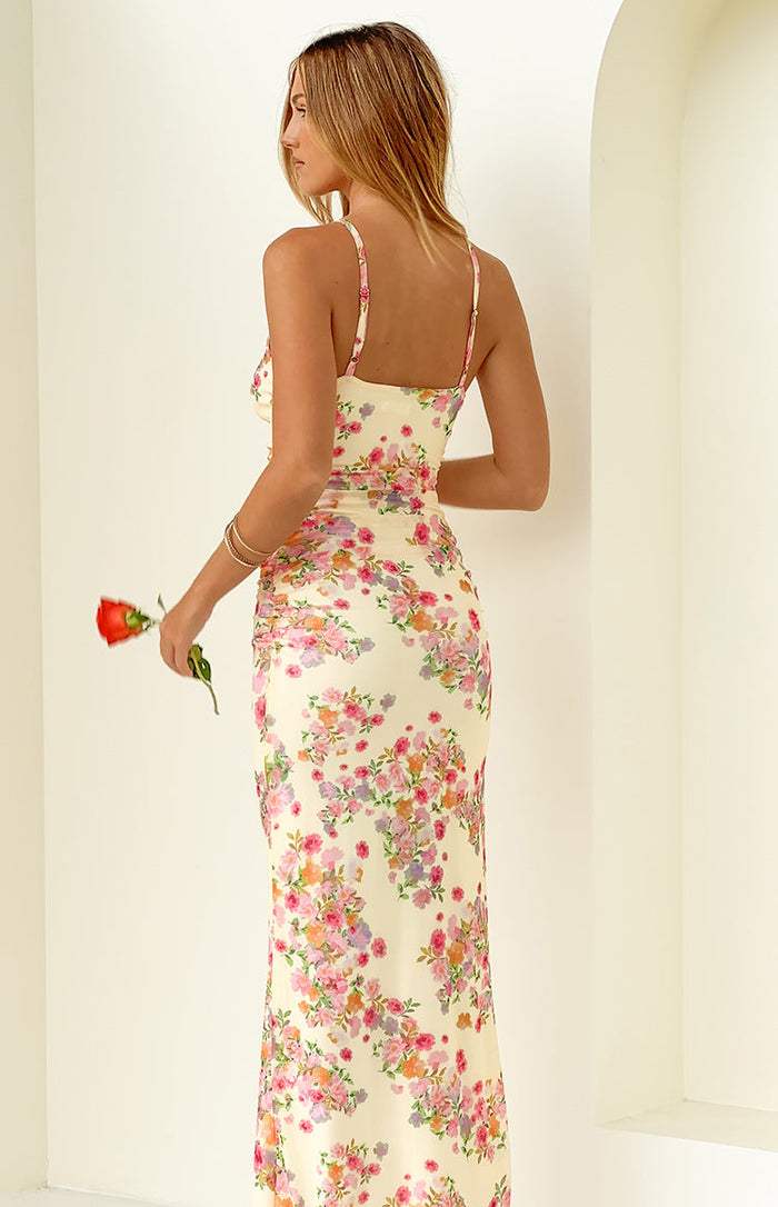 Rear-side view of a yellow floral maxi dress with thin spaghetti straps and ruched detailing on the side