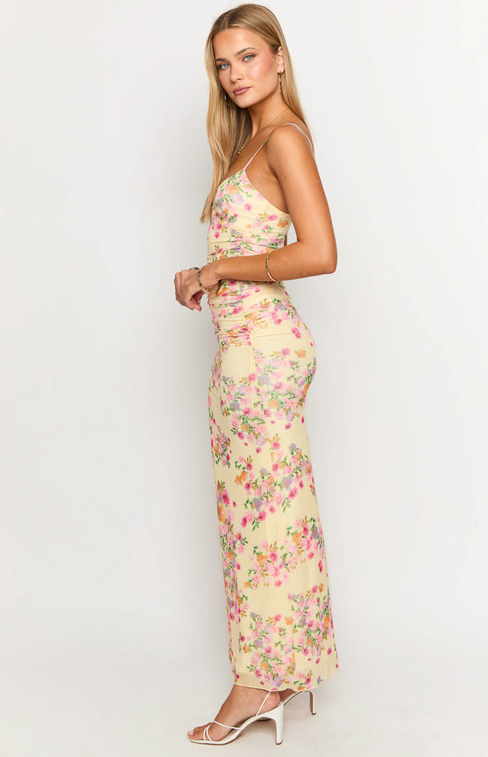 Side view of a yellow floral maxi dress with spaghetti straps, ruched side detail, and a flowy skirt