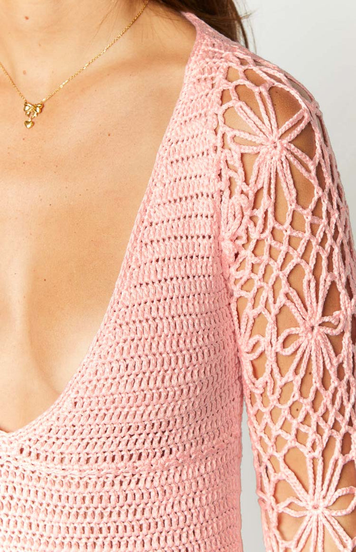 Close-up of the pink crochet mini dress showing the open floral pattern on the long sleeve and tighter stitch on the body