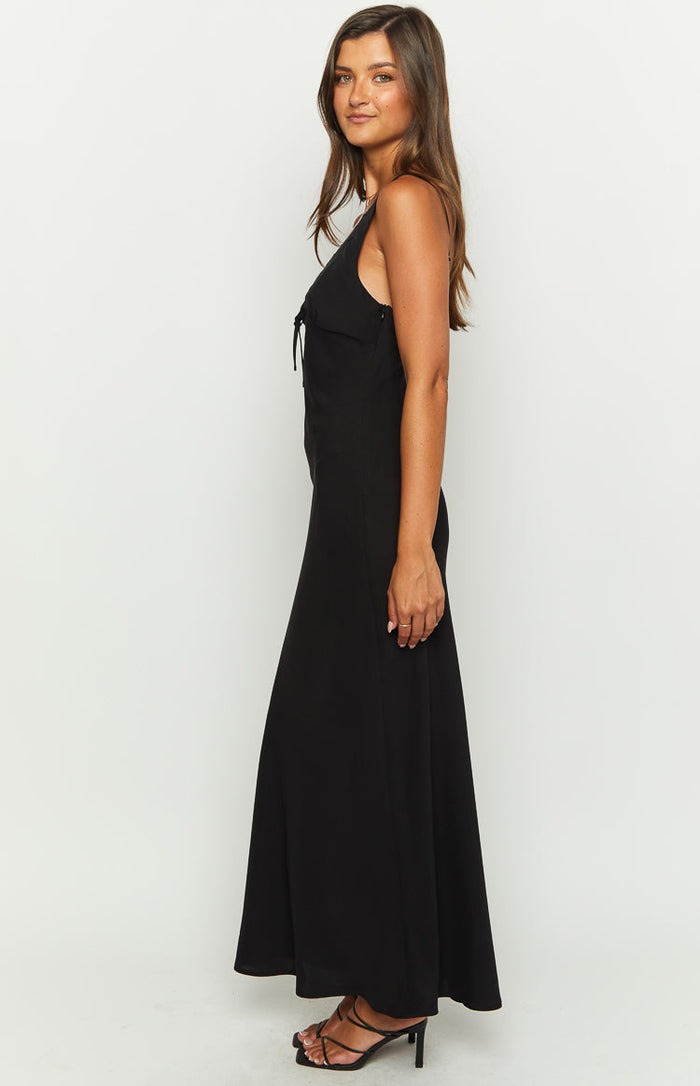 Side view of a black maxi dress showing the tie-front bust detail, thin spaghetti straps, and flowy skirt