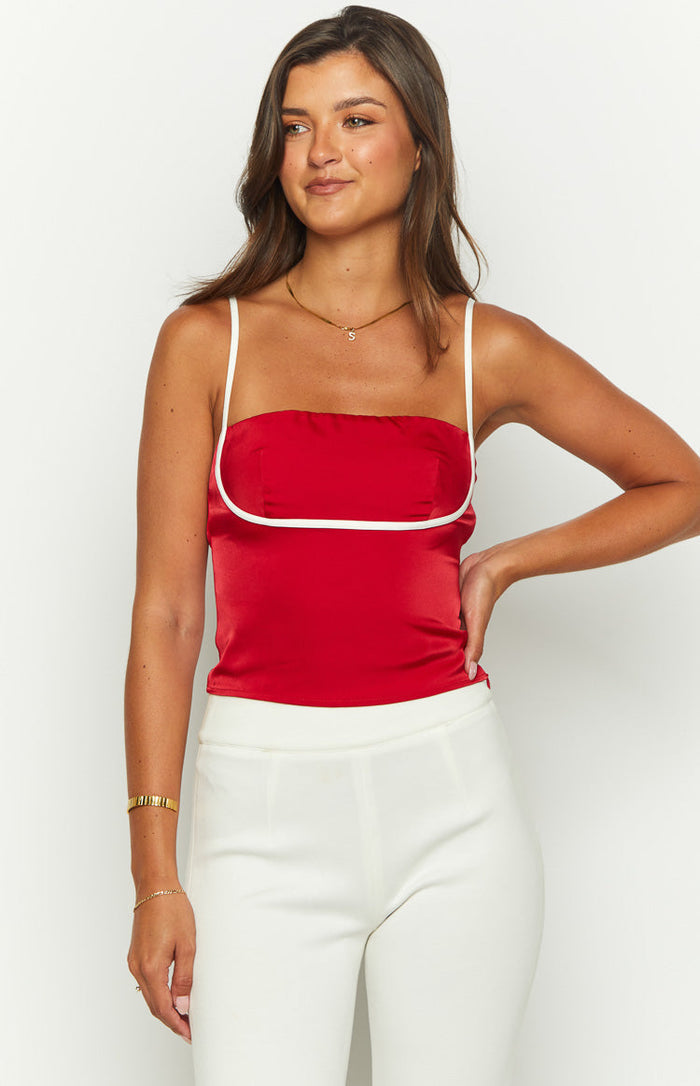 Close-up front view of a red satin top with a square neckline and white piping detail