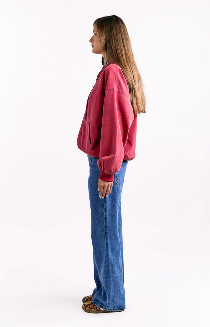 Side view of a washed red oversized hooded jacket with dropped shoulders and ribbed cuffs