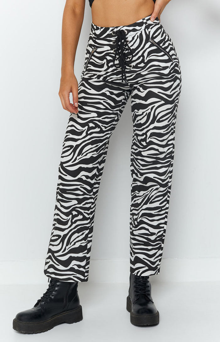 Black and white zebra print high-waisted pants with a lace-up front and diagonal zip pockets