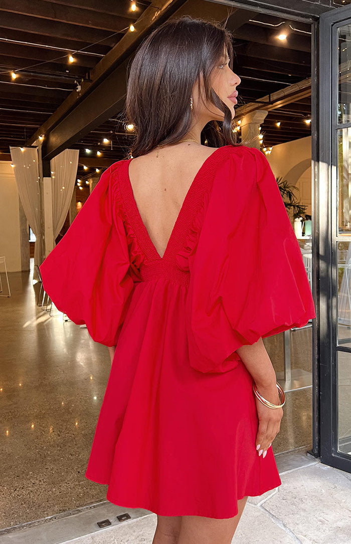 Rear-side view of a red mini dress with a deep V-back, shirred back trim, and voluminous puff sleeves